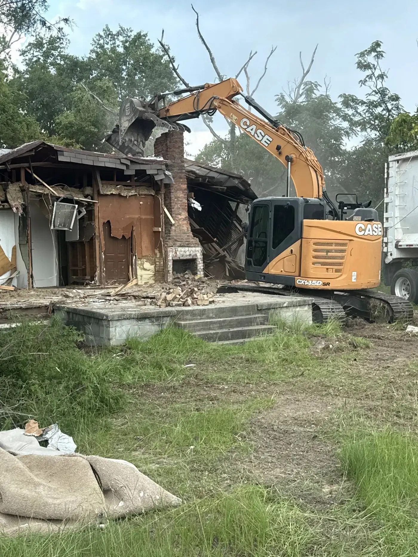 CASE excavator pulling down the brick chimney of a house during a demolition